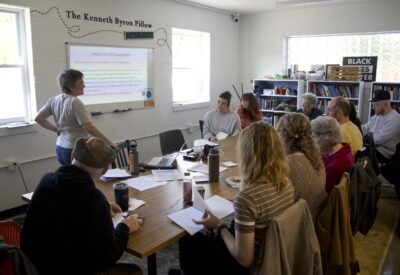 Image of storygathering training in which Elissa Yancey presents to participants gathered around a table.