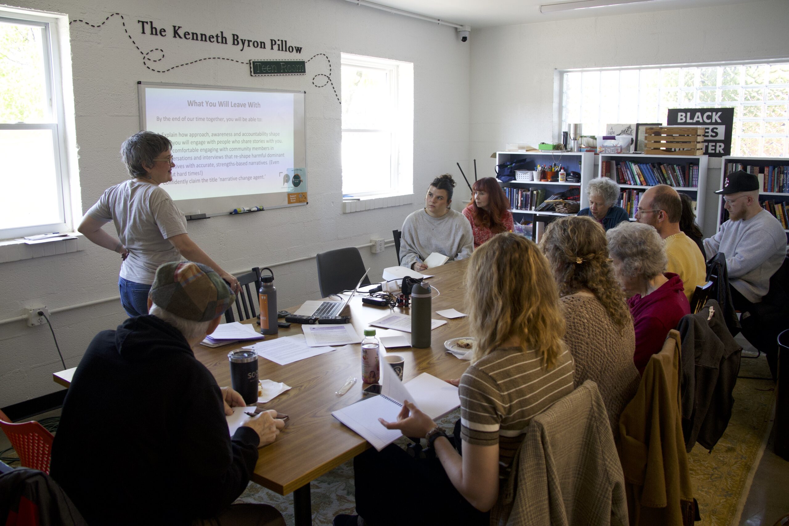 Image of storygathering training in which Elissa Yancey presents to participants gathered around a table.